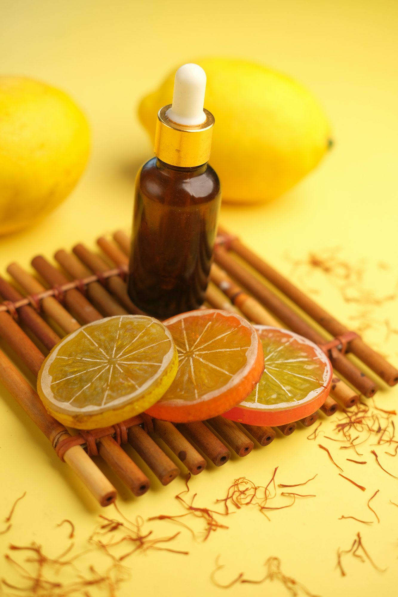 Essential oil bottle and lemon on yellow background