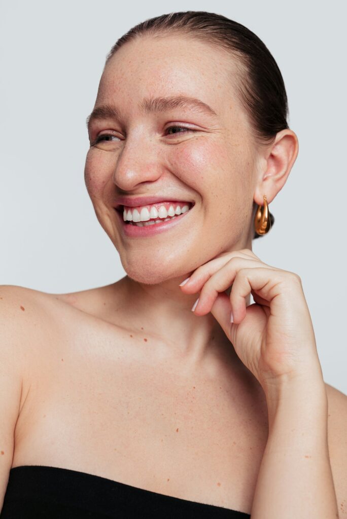 Happy woman with glowing skin touching chin in studio