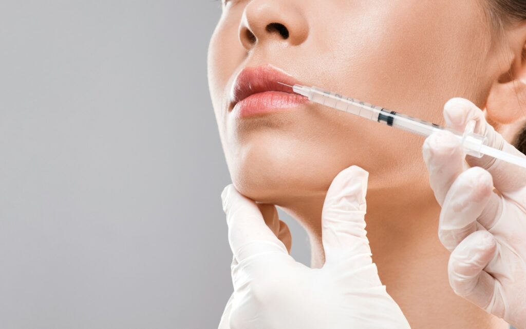 Nurse making lip injection for young woman