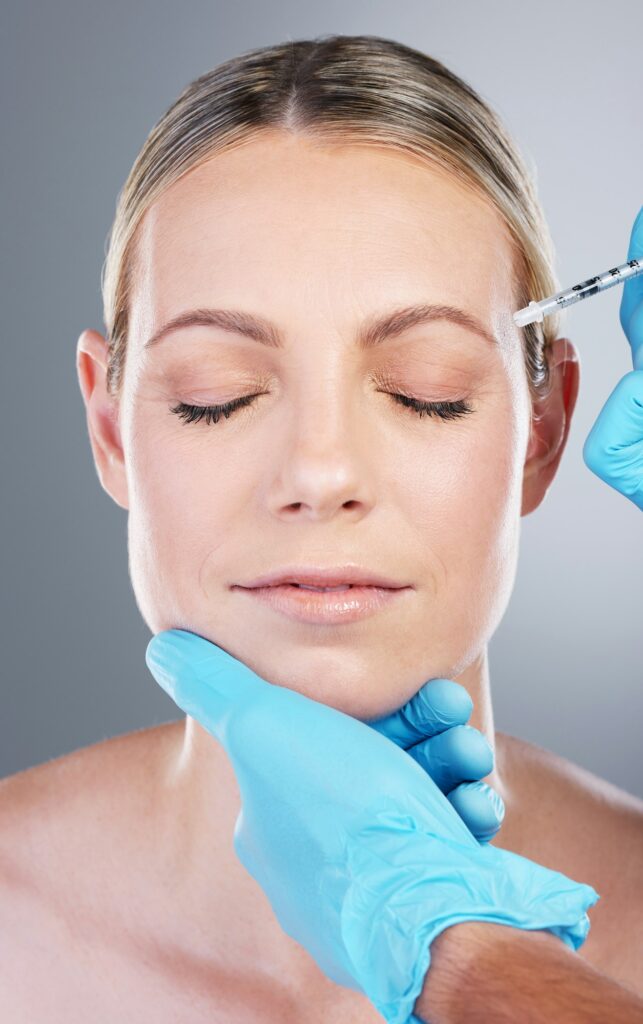 Studio shot of an attractive mature woman receiving a botox injection against a grey background